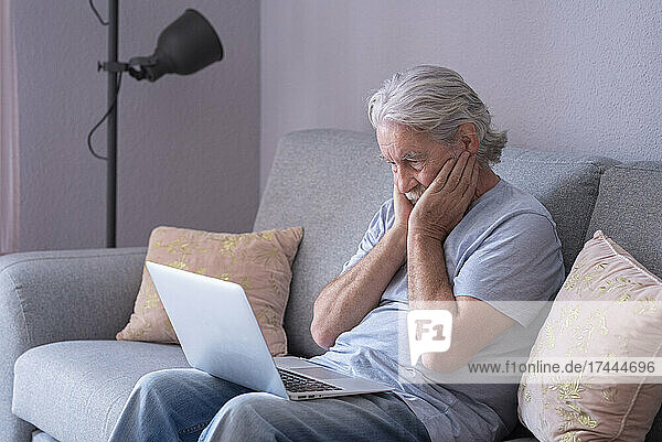 Man with head in head sitting on sofa at home