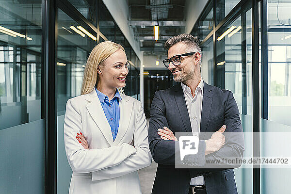 Smiling male and female business professionals looking at each other in office