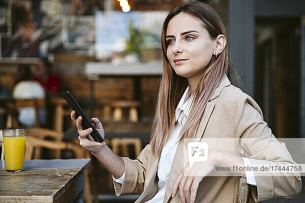 Female business professional with mobile phone sitting at cafe