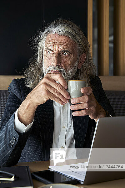 Geschäftsmann mit Kaffeetasse sitzt im Hotelcafé