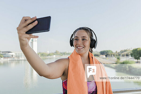 Sportlerin lächelt  während sie ein Selfie mit dem Mobiltelefon macht