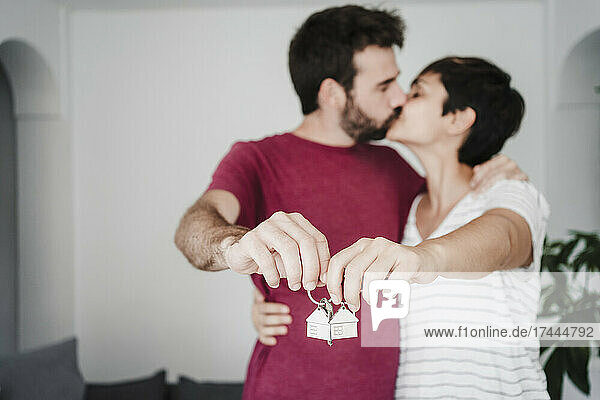 Liebevolles Paar küsst sich  während es den Hausschlüssel in der Hand hält