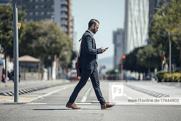 Male professional using mobile phone while walking in city