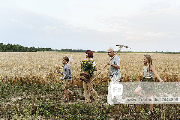 Family with tansy flowers and rake walking on field