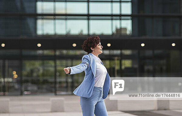 Female professional enjoying while dancing outside office building