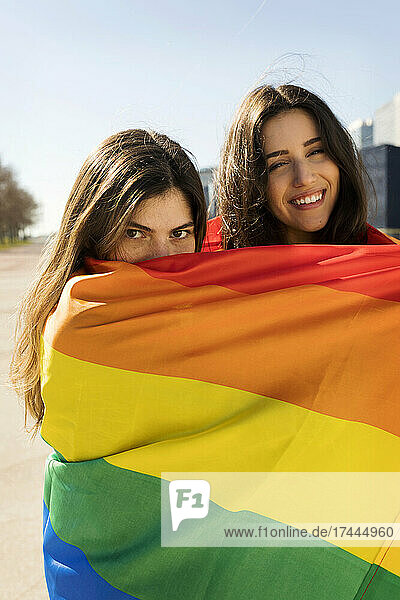 Young lesbian couple covered in rainbow flag