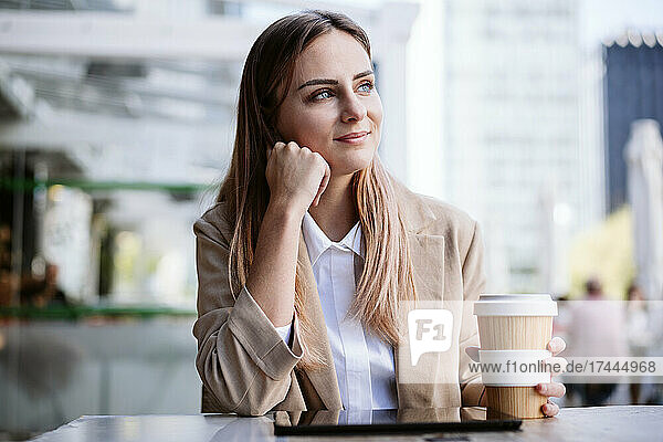 Thoughtful businesswoman with disposable coffee cup at terrace