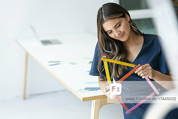 Female architect holding house shape ruler at workplace