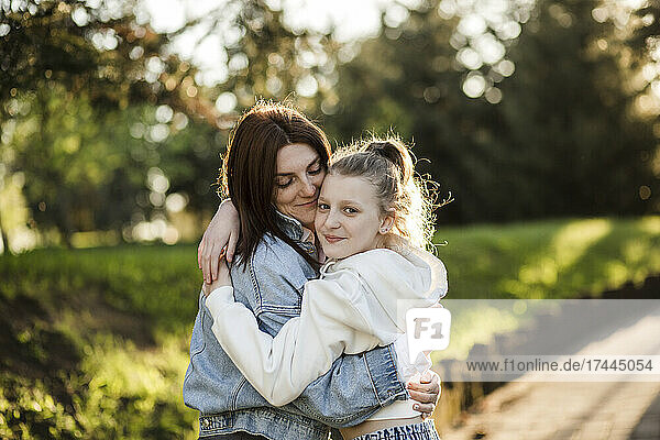Mother hugging daughter at park