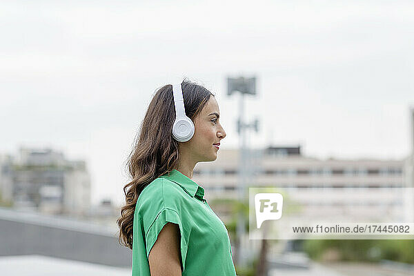 Young woman listening music through wireless headphones