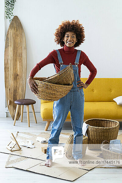 Afro woman with wicker baskets standing in living room