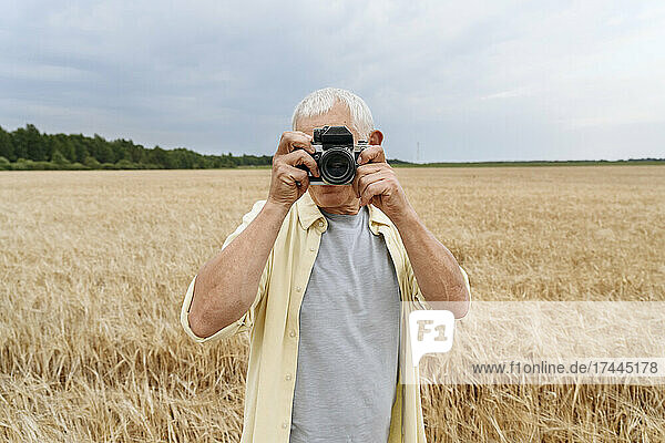 Man photographing through camera on wheat field