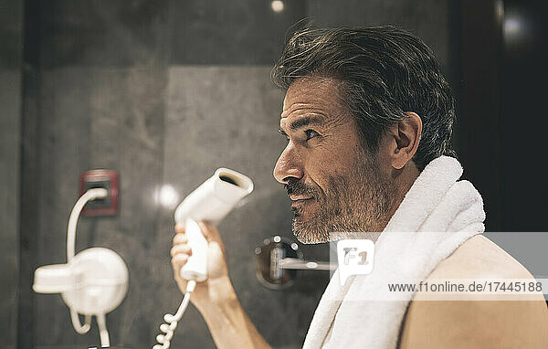 Man drying hair in hotel room