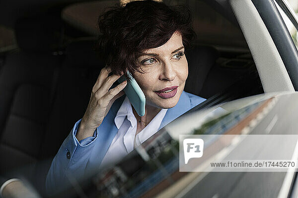 Beautiful female professional talking on smart phone in car
