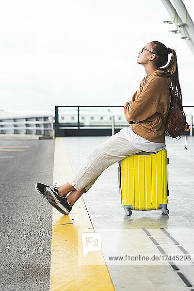 Woman sitting on luggage at airport