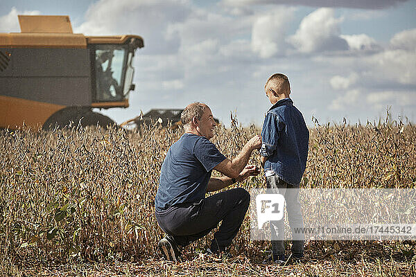 Smiling senior male farmer looking at grandson while working in field