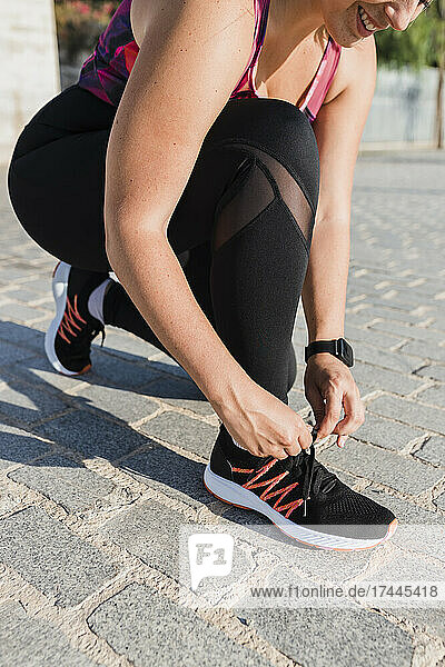 Female athlete tying shoelace during sunny day