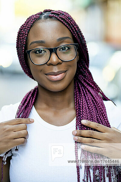 Smiling young woman with braided hair wearing eyeglasses