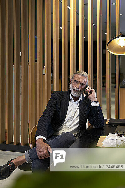 Mature male professional talking on smart phone at desk in hotel
