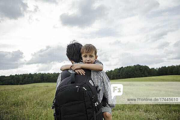 Father with backpack carrying son at meadow