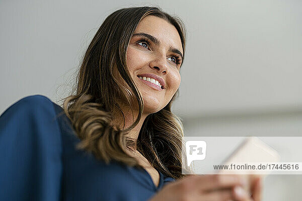Smiling young businesswoman with smart phone in office