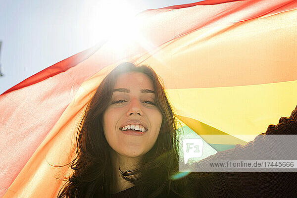 Junge Frau mit Regenbogenfahne an einem sonnigen Tag