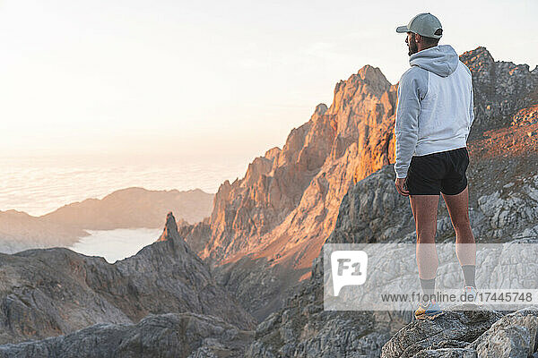 Male tourist looking at mountains while standing on rock  Picos de Europe  Cantabria  Spain