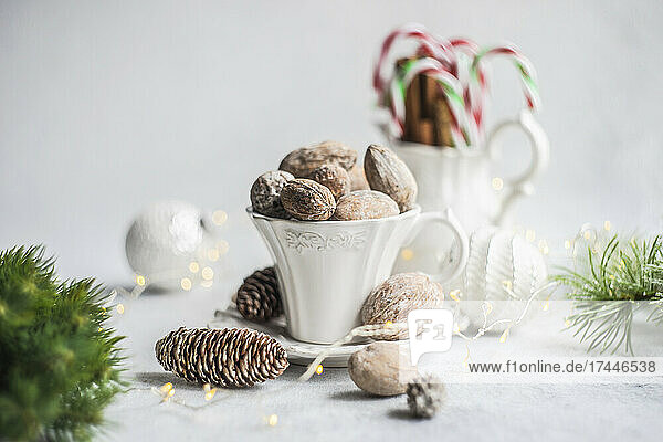 Vintage cup full of nuts,  cinnamon sticks and candy canes on concrete background