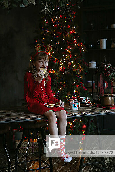 Dressed up girl eating christmas cookies
