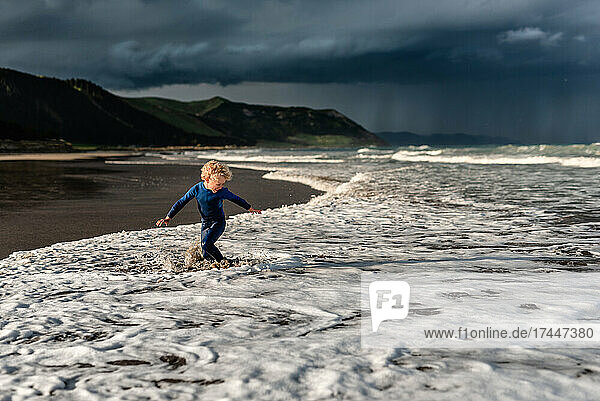 Happy child playing at beach with dramatic sky in background