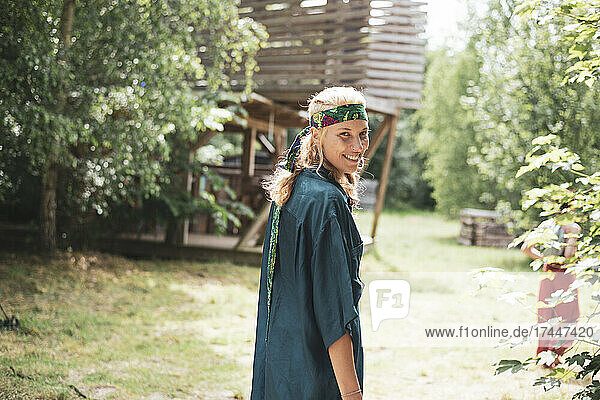 Smiling blond bohemian woman walking in nature at festival in Poland