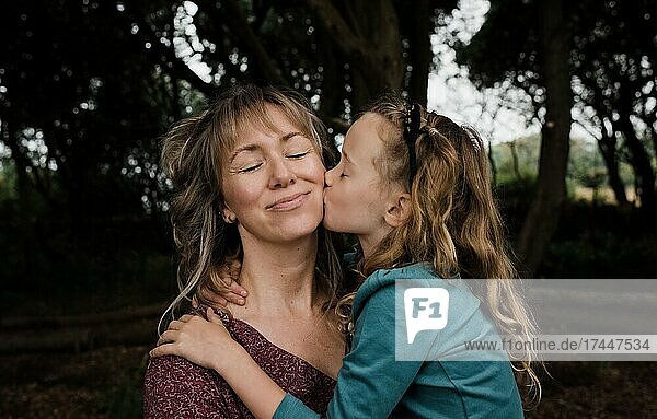 daughter kissing mother on the cheek whilst outdoors