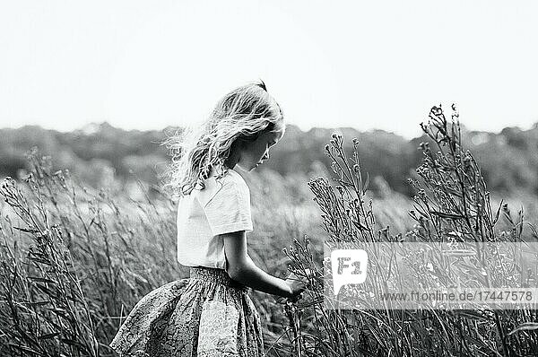 girl walking through flowers thoughtfully in summer