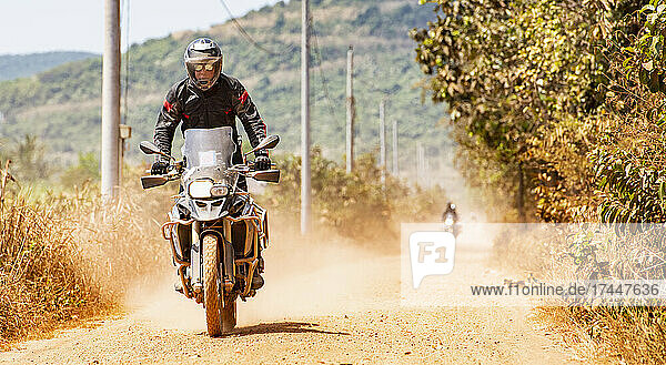 Man riding his adventure motorbike on dusty road in Cambodia