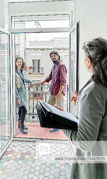 Happy Diverse Couple Examining Apartment Scheme With Realtor