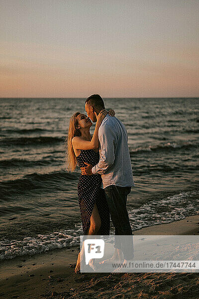 A couple in love stands embracing by the sea.