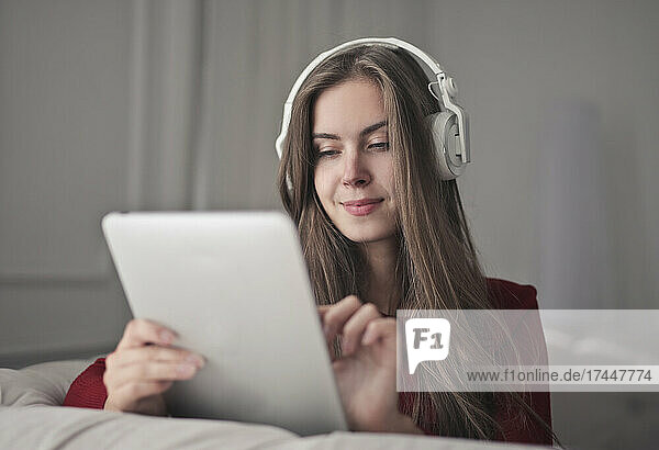 young woman uses a tablet and listens to music