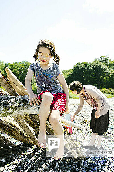 Straight on view of a child sitting on driftwood