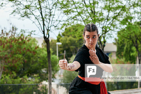 Woman in uniform praticing martial arts in a park
