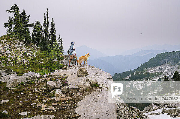 Male hiker and dog standing on a ridge in the alpine lakes wilderness