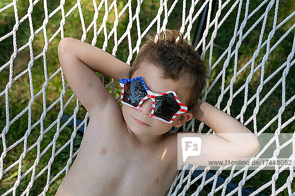tight shot of a boy with a dreamy expression relaxing in a hammock
