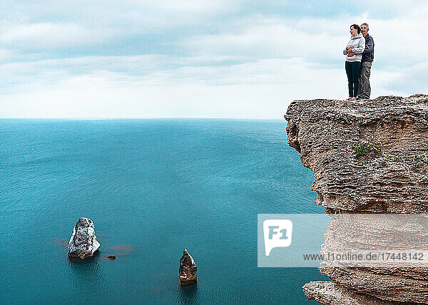 Man and woman standing on a rock above the sea  embracing.