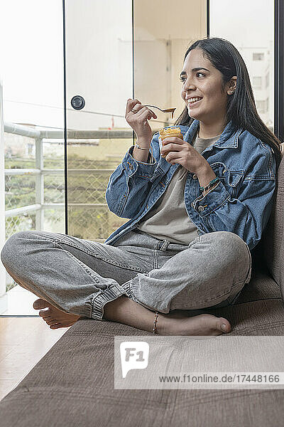 Vertical photo of a smiling woman eating homemade cashew butter