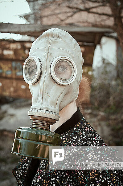 girl in a gas mask and a dress with a plant in her hands during quarantine  in an empty city