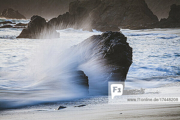 Waves splash and crash against rocks on beach Big Sur  California