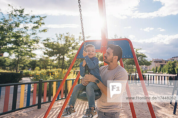 Father and his son playing with a zip line in a park
