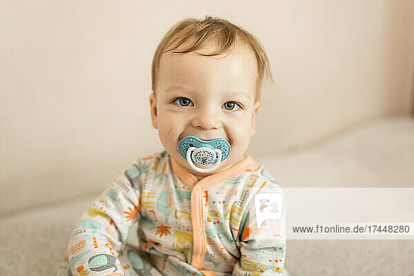 Portrait of infant boy smiling with dummy