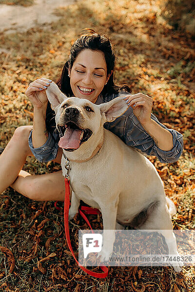 Happy woman having fun with her Labrador puppy outdoors