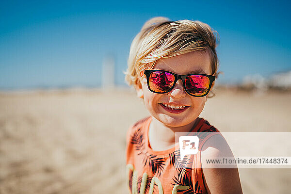 Happy smiling young boy wearing sunglasses at beach