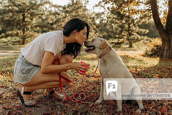 Happy woman kissing fun with her Labrador puppy outdoors